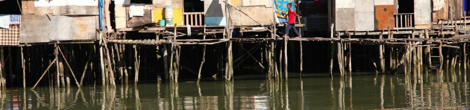 A boy crosses a plank walkway leading to dwellings built on stilts on the waters of the South China Sea in Kampung Numbak Village, off the coast of Sabah State in East Malaysia on the island of Borneo.
