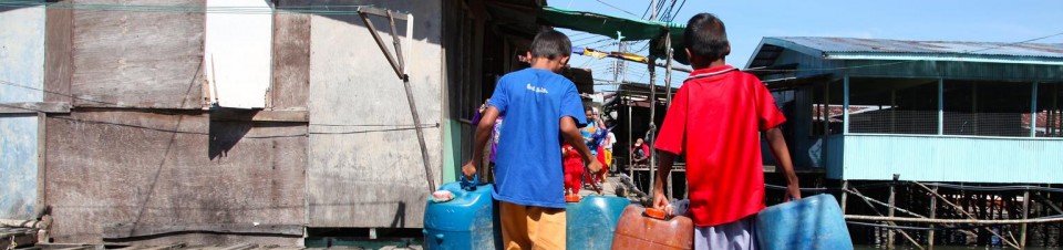 Deux enfants gagnent de l’argent en transportant jerricanes de pétrole, village de Kampung Numbak, sur la mer de Chine, au large des côtes de l’état de Sabah (Ile de Bornéo). 
