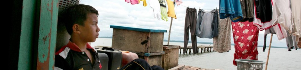 Twelve-year-old Zaini Ali, a member of the Bajau ethnic group, sits under laundry lines on a dock outside his home, on Timbang Island in the state of Sabah. 
